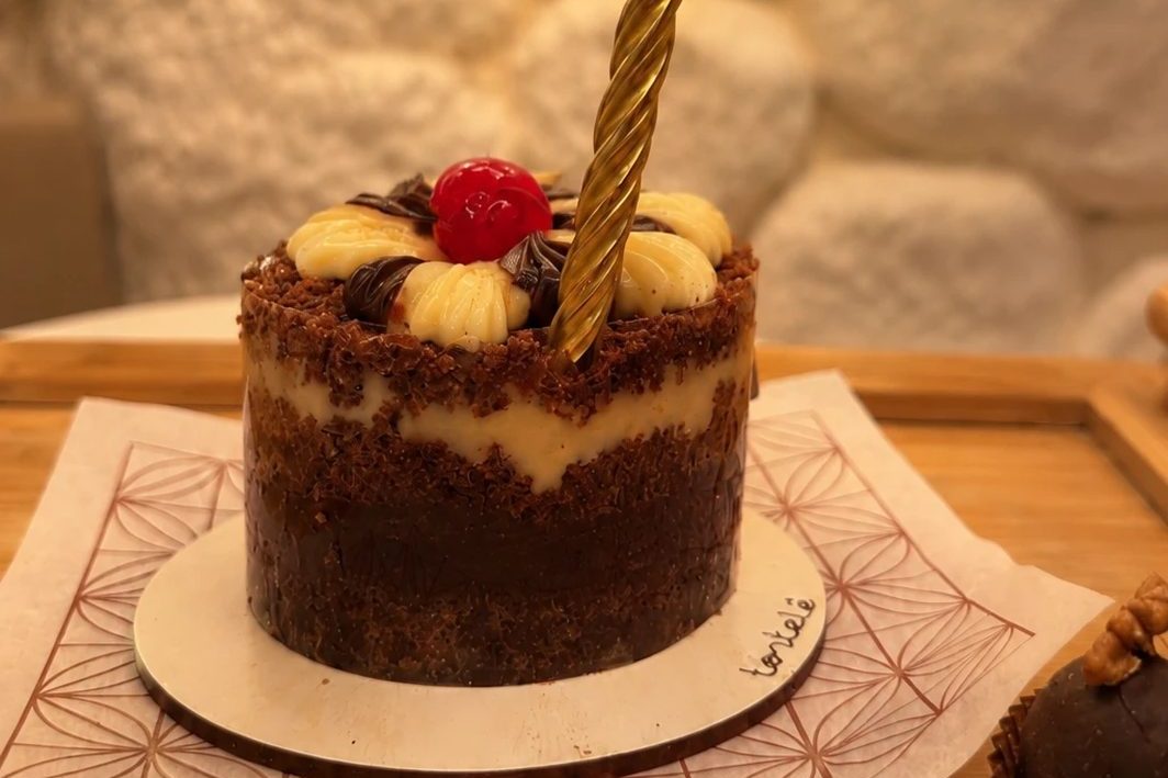 Bolinho de aniversário com vela dourada, sobre uma bandeja de madeira